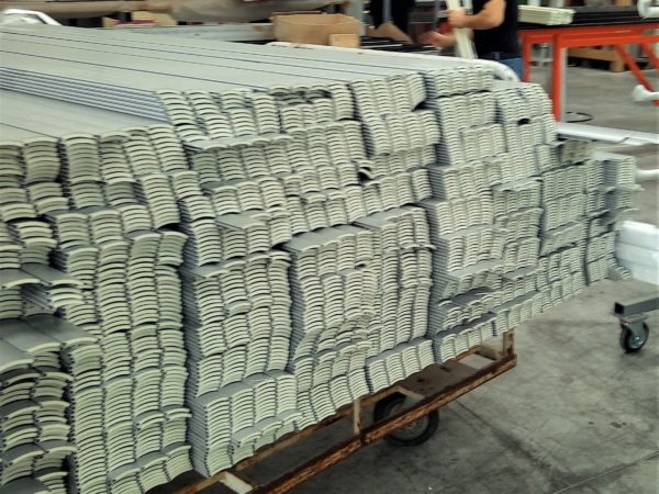 Centinaia di stecche in alluminio appena tagliate prima di essere assemblate su tavolo di lavoro